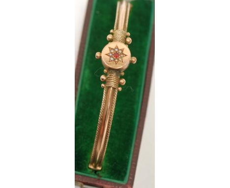VICTORIAN 9ct GOLD NARROW, HINGE OPENING BANGLE, the top having a circular disc set with a tiny ruby and seed pearl cluster, 