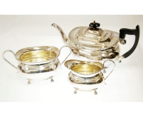 THREE PIECE ELECTROPLATED TEA SET of rounded oblong form, with bobbin and reel borders and paw feet, THE TEAPOT with black kn