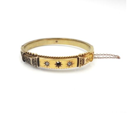 A 15ct gold and diamond bangle, the front star set with two cushion shaped diamonds, (the central gemstone lacking), otherwis