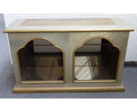 R. Dubarry; a 20th century brass veneered side cabinet, with a pair of arched recesses enclosing glass shelves, 136cm wide x 