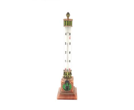 A gold and enamel mounted pink hardstone table thermometer of column form, raised on a square base, the base applied with two