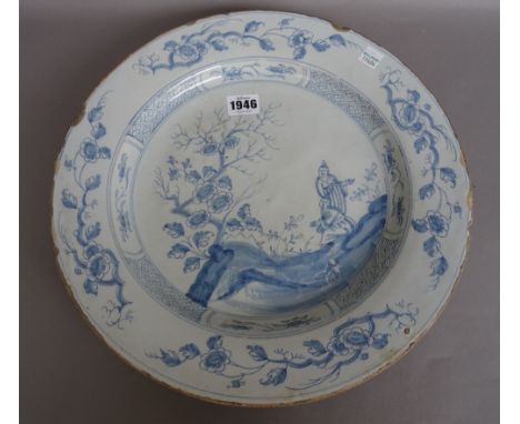 An English delftware blue and white large plate, perhaps Bristol,circa 1760, painted with two Oriental figures  beside a flow