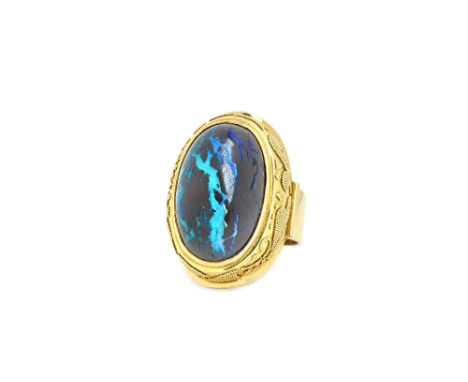 A gold and wood opal single stone ring, mounted with an oval cabochon wood opal, within a beaded raised surround, detailed 75