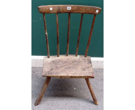 An early 19th century primitive ash and elm stick back chair, with solid seat on three staked supports, 57cm wide x 78cm high