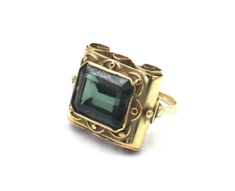 A gold ring, mounted with a cut cornered rectangular emerald cut synthetic green spinel, the mount with bead and wirework app