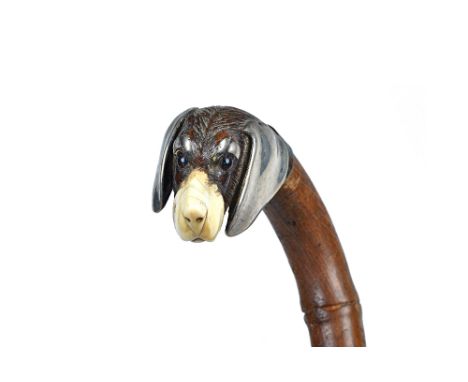 A Black Forest walking stick, circa 1900, with carved dog's head pommel, ivory nose/mouth and white metal mounts, on a bamboo