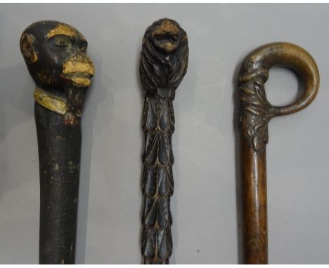 An ebonised 'lion's head' carved wooden walking stick, 19th century, with foliate carved shaft (87cm), a polychrome painted '