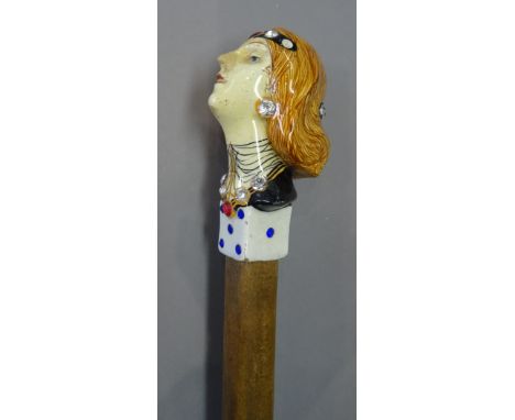 An Italian figural pottery walking stick pommel, 20th century, modelled with a bust of an Art Deco lady, above a die, over a 