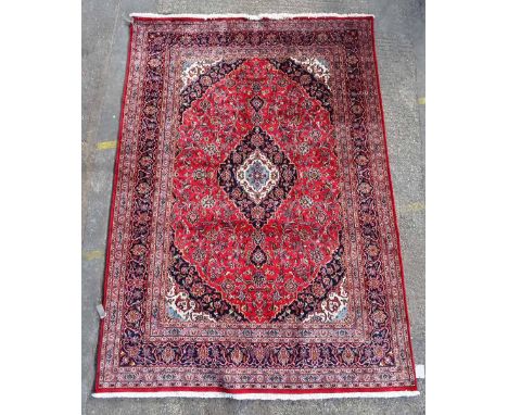 A Kashan carpet, Persian, the madder field with a dark indigo, ivory and light indigo medallion, matching spandrels, all with