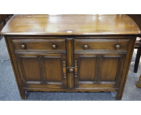 An Ercol sideboard, oversailing top, two short drawers over two door cupboard, stile feet. 85cm high x 124cm wide x 48cm deep