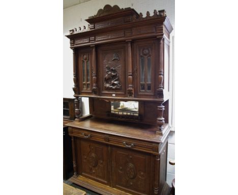 A Flemish oak cupboard, shaped pediment, central cupboard carved with hunting scene flanked by astragal glazed cupboards and 