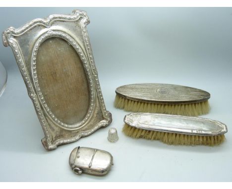 A silver fronted photograph frame, two silver backed clothes brushes, a silver vesta case/sovereign case (42g, a/f) and a sil