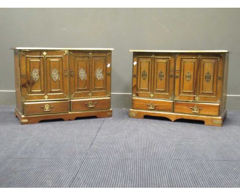 An elm or hardwood and brass bound low cabinet, with two fielded panel doors enclosing an arrangement of small drawers, on br