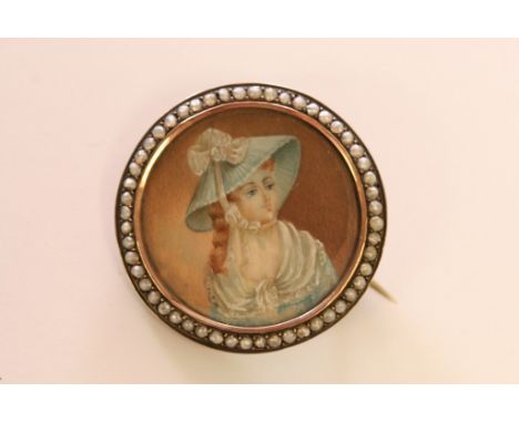 A white metal brooch of circular form inset with a portrait miniature on ivory with seed pearl surround