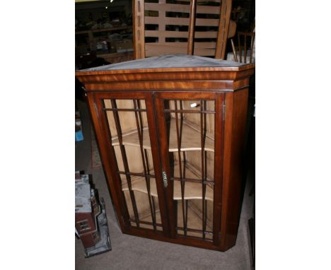 A George III mahogany corner unit with glazed doors above a single cupboard door on bracket feet 