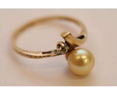 A ladies yellow gold ring set with a single diamond and a single pearl