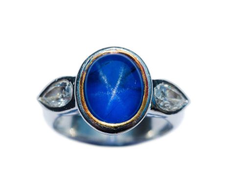 A platinum set natural star sapphire and diamond ring. The oval cabochon sapphire weighing 5.68 carats, with six rayed star a