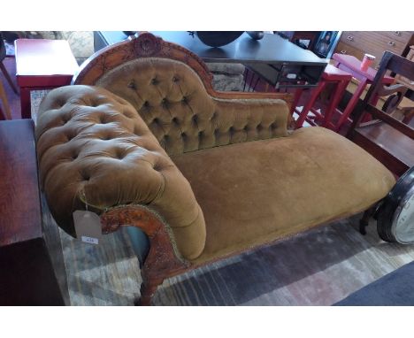 A Victorian mahogany chaise lounge having carved frame with green velour button back upholstery raised on turned legs and cas