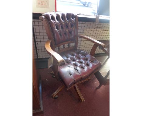 A 20th Century captains swivel chair with red leather button back upholstery.