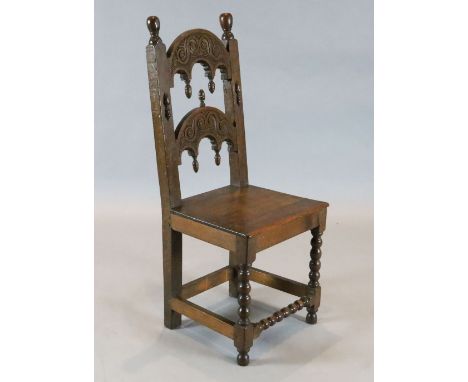 A 17th century Derbyshire oak side chair, with carved and turned arched back and solid seat on bobbin turned legs, W.1ft 4in.