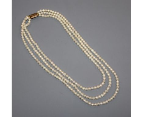 A triple strand cultured pearl necklace with engraved yellow metal clasp, 50cm.
