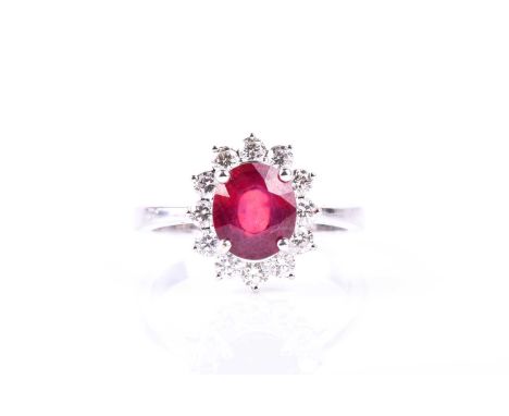 An 18ct white gold, diamond, and ruby cluster ring, set with a mixed oval-cut ruby within a border of round brilliant-cut dia