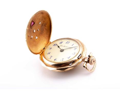 A yellow metal ladies fob watch, of round design, the hinged lid inset with a trillion-cut red stone and six small old-cut di