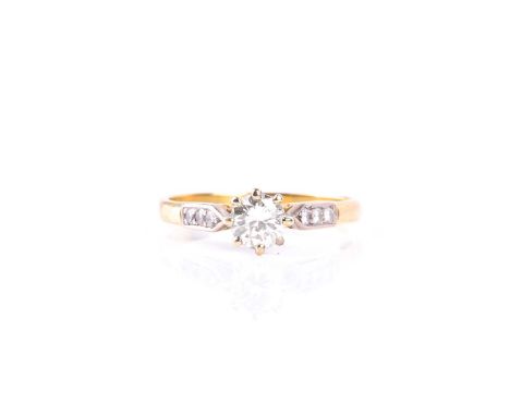 A single stone diamond ring, the round brilliant cut diamond in eight claw mount to three stone dimond shoulders and plain 18