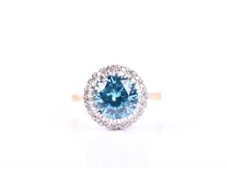 A yellow metal, diamond, and blue stone ring, set with a round-cut stone approximately 9 mm diameter, surrounded with a borde