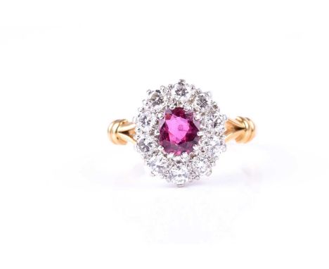 A ruby and diamond cluster ring, the oval cut ruby claw mounted within a border of brilliant cut diamonds, to slightly raised
