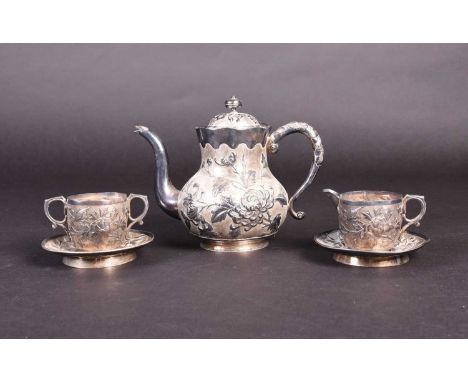 A Chinese silver part tea set, comprising teapot, milk jug, sugar bowl and two saucers, each with embossed foliate decoration