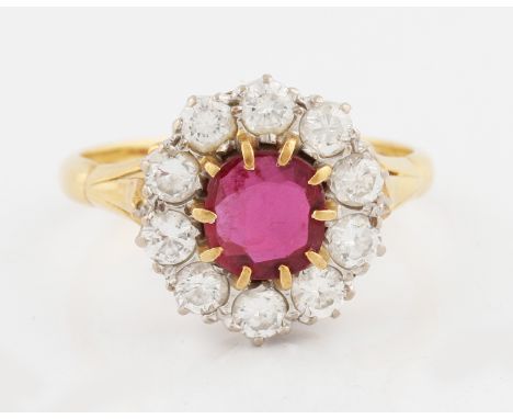 An 18ct yellow gold synthetic ruby and diamond cluster ring, set with a central cushion cut flux-melt synthetic ruby, measuri