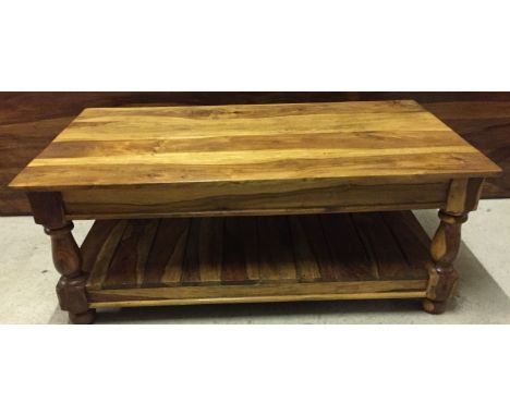 A rectangular solid wood Indian rubber wood coffee table. With lower shelf. Approx. 110 x 61cm.