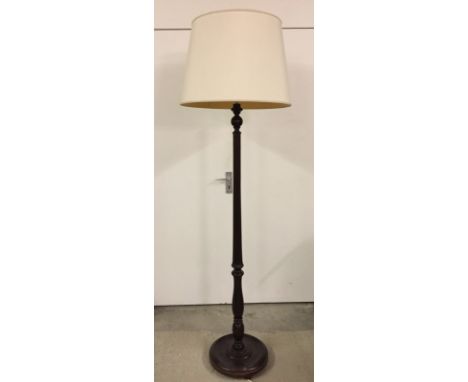 A dark wood carved standard lamp with cream coloured lampshade.  