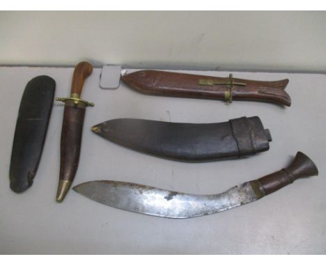 A Kukri with a leather scabbard together with two knifes and an axe handleLocation: 