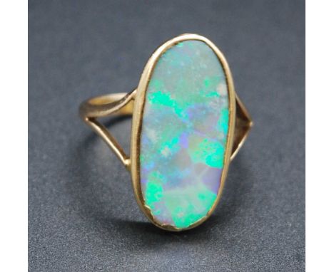 A yellow metal opal dress ring, comprising an oblong crystal opal exhibiting blue and green harlequin colour pattern, with bi