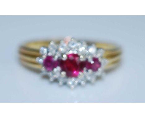 An 18ct yellow and white gold, ruby and diamond triple cluster ring, comprising three graduated round rubies within a border 