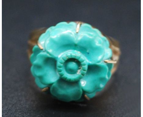 A 9ct gold turquoise dress ring, the five-claw set turquoise carved as a flower head, dia.17mm, to a plain band with pierced 