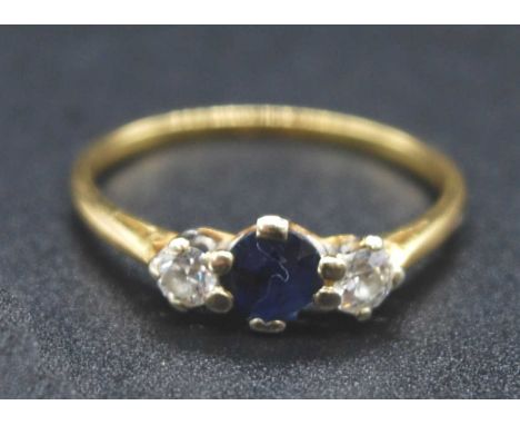 An 18ct gold, sapphire and diamond three-stone ring, the centre round cut sapphire flanked to either side with a four-claw se