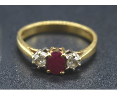 An 18ct gold, ruby and diamond three-stone ring, arranged as a four-claw set oval cut ruby weighing approx 0.5 carats, flanke