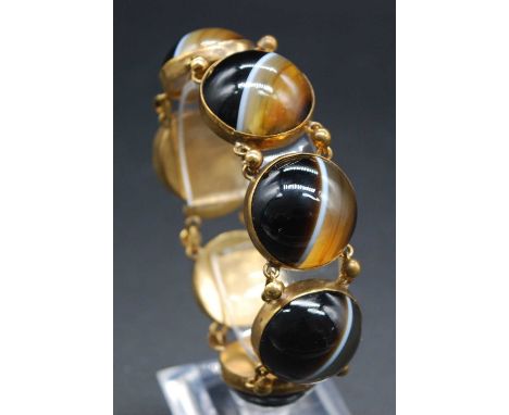 An early 20th century gilt metal and banded agate set bracelet, arranged as seven large cabochon stones in closed backs, 17cm