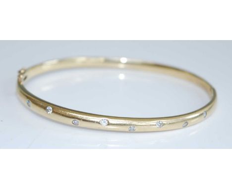 A contemporary yellow metal and diamond set hinged bangle, set with eight brilliant cut diamonds, each weighing approx 0.04 c