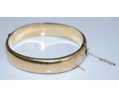 A 9ct yellow gold half engraved oval hinged bangle with box clasp and safety chain, bangle width 12.5mm, inner diameter 60 by