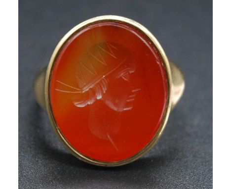 A Victorian yellow metal carnelian set signet ring, the oval matrix carved with a profile portrait of a young Roman, stamped 