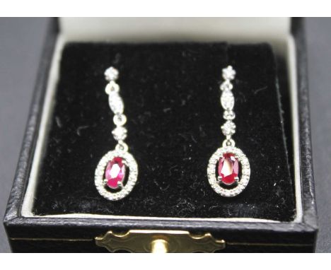 A pair of Edwardian style 18ct white gold ruby and diamond ear pendants on post fittings, the four claw set oval cut rubies w