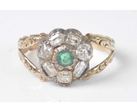 A yellow and white metal, emerald and diamond circular cluster ring, comprising a centre round faceted emerald within a borde