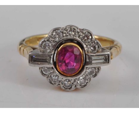 A yellow and white metal, ruby and diamond oval cluster ring, featuring a centre oval faceted ruby within a yellow bezel sett