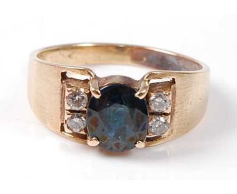 A yellow metal, sapphire and diamond dress ring, featuring a teal coloured oval sapphire with two round brilliant cut diamond