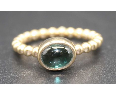 A 9ct yellow gold tourmaline dress ring with an oval cabochon cut green tourmaline in a bezel setting attached to a beaded sh