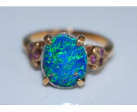 A yellow metal opal doublet dress ring, having three round rubies set in a leaf design to each shoulder, opal doublet dimensi